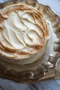 a cake with white frosting sitting on top of a glass plate next to a fork