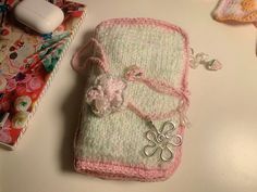 a crocheted cell phone case sitting on top of a table next to other items