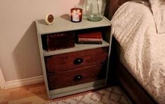 a bedroom with a bed, night stand and two candles on top of the nightstand