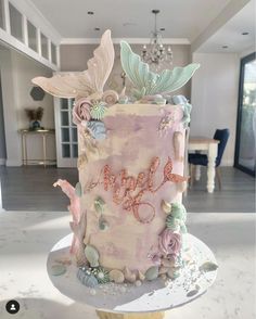 a pink and blue cake sitting on top of a white table next to a chandelier