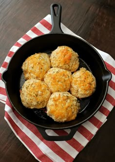 a skillet filled with cheese balls on top of a red and white striped napkin