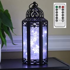 a lit up lantern sitting on top of a black table next to a remote control