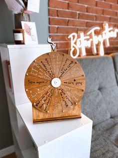 a wooden spinning wheel sitting on top of a white table next to a gray couch