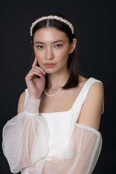 a woman in a white dress with pearls on her head