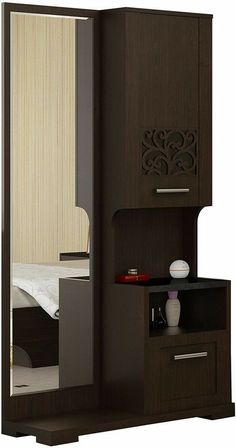 an open wardrobe with a mirror on the door and drawers below it, in front of a bed