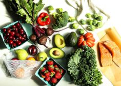 various fruits and vegetables are laid out on a table top, including tomatoes, broccoli, avocado, cherries, lettuce