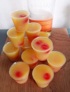 small glasses filled with liquid sitting on top of a wooden table