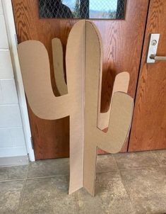 a cardboard cactus sitting in front of a door with the letter h on it's side