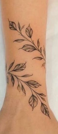 a woman's foot with a tattoo on it that has leaves growing out of it