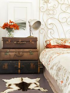 three suitcases stacked on top of each other in front of a bed with a cowhide rug