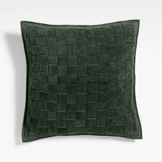 a dark green pillow with squares on it and a white wall in the back ground