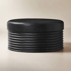 a black round ottoman sitting on top of a table