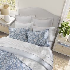 a bed with blue and white comforters in a bedroom next to a window,