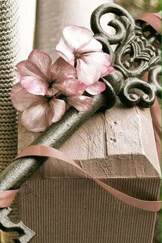 some pink flowers are on top of a piece of metal and ribbon next to a window sill