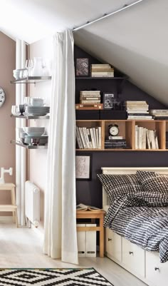 a bed sitting under a window next to a shelf filled with books and other items