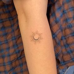 a woman's arm with a small sun and moon tattoo on her left arm