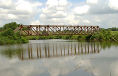 a bridge over a river with water and trees in the background