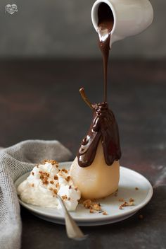 a dessert with chocolate sauce and whipped cream on a white plate next to a spoon