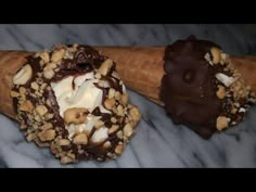 two cones filled with ice cream and chocolate on top of a marble countertop next to each other