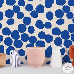 three vases are lined up in front of a wall with blue circles on it