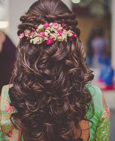 the back of a woman's head with flowers in her hair and long curls