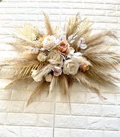 an arrangement of flowers and grass on a brick wall