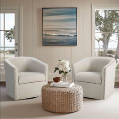 a living room with two white chairs and a coffee table in front of a window