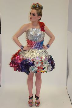 a woman standing in front of a white backdrop wearing a dress made out of flowers