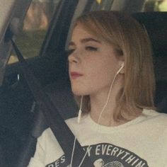 a woman sitting in the back seat of a car wearing headphones and listening to music