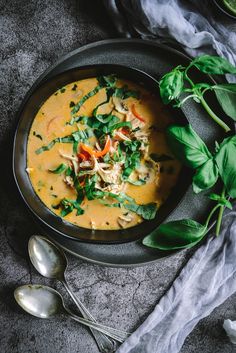 a bowl of soup with spinach, carrots and other vegetables on the side