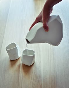 someone pours water into small cups on a table