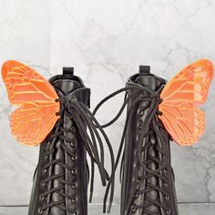 a pair of black boots with orange butterfly wings