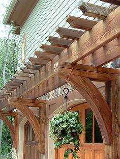 a wooden pergolan attached to the side of a house with potted plants