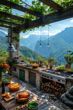 an outdoor kitchen with lots of food on the table and mountains in the back ground