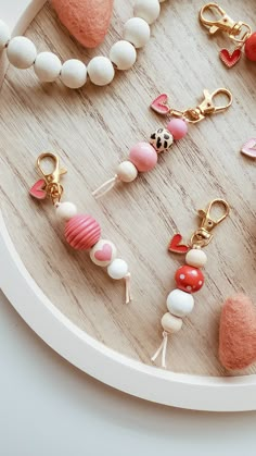 several different types of beads and charms on a white tray next to a pink heart