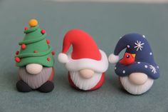 three small figurines are sitting next to each other on the floor, one is wearing a santa hat