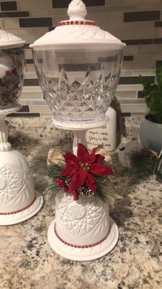 two christmas bells sitting on top of a counter next to a vase with flowers in it