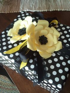 a gift wrapped in black and white polka dot paper with yellow flowers