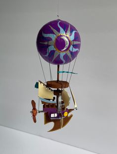 a colorful hot air balloon floating in the sky with other objects attached to it's sides