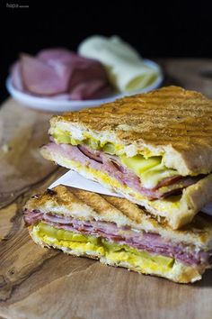 a sandwich cut in half sitting on top of a wooden cutting board