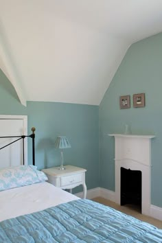 a bedroom with blue walls and a white fireplace in the corner next to a bed