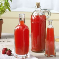 two bottles filled with liquid sitting on top of a table next to some strawberries