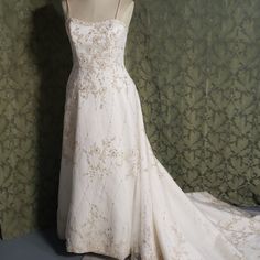 a white wedding dress on display in front of a green wall