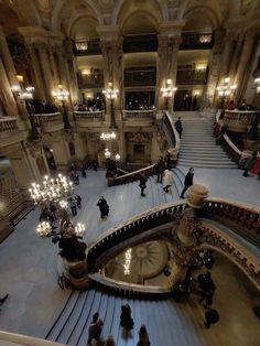 people are walking up and down an escalator in a building with chandeliers hanging from the ceiling