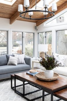 a living room with couches, tables and lamps on the ceiling in front of large windows