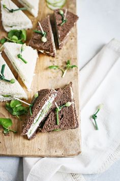 a wooden cutting board topped with sandwiches and veggies