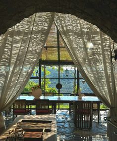 the inside of a house with large windows and sheer curtains on it's sides