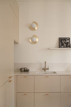 a kitchen with white cabinets and gold trim on the wall, two plates above the sink