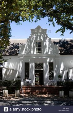 an old white house with large trees in the front yard