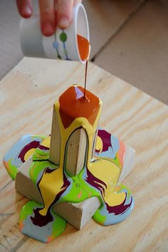 someone is pouring something into a cup on top of a wooden table with other items